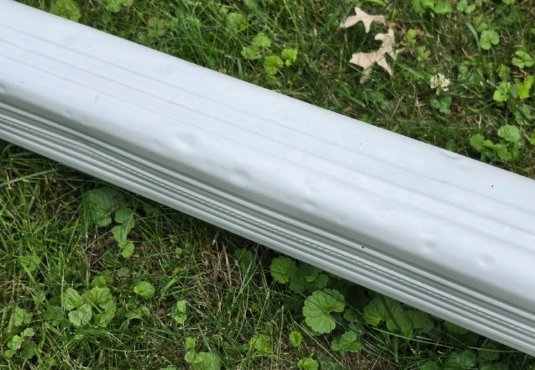 Dented aluminum downspout from hail impact